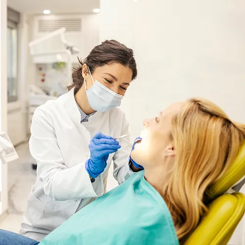 dentist wearing mask using dental tool in patient's mouth
