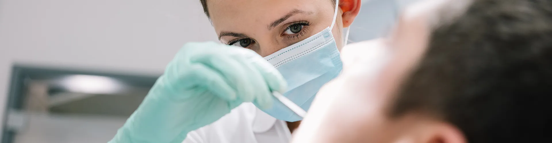 female dentist using dental tool in male patient's mouth