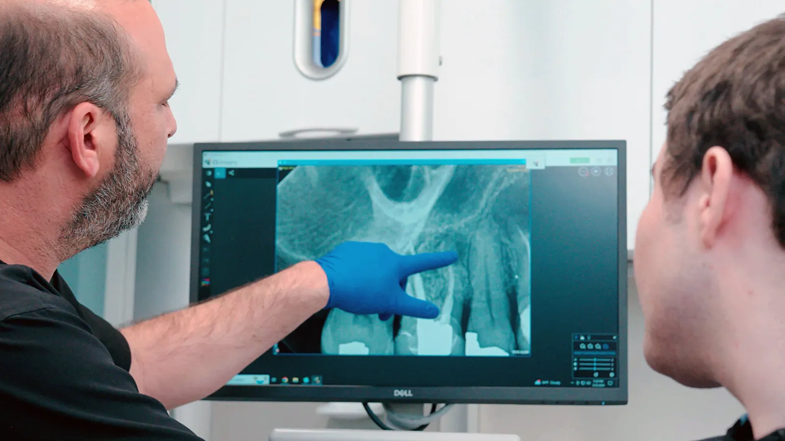 Dentist showing dental X-rays on a screen to a patient.